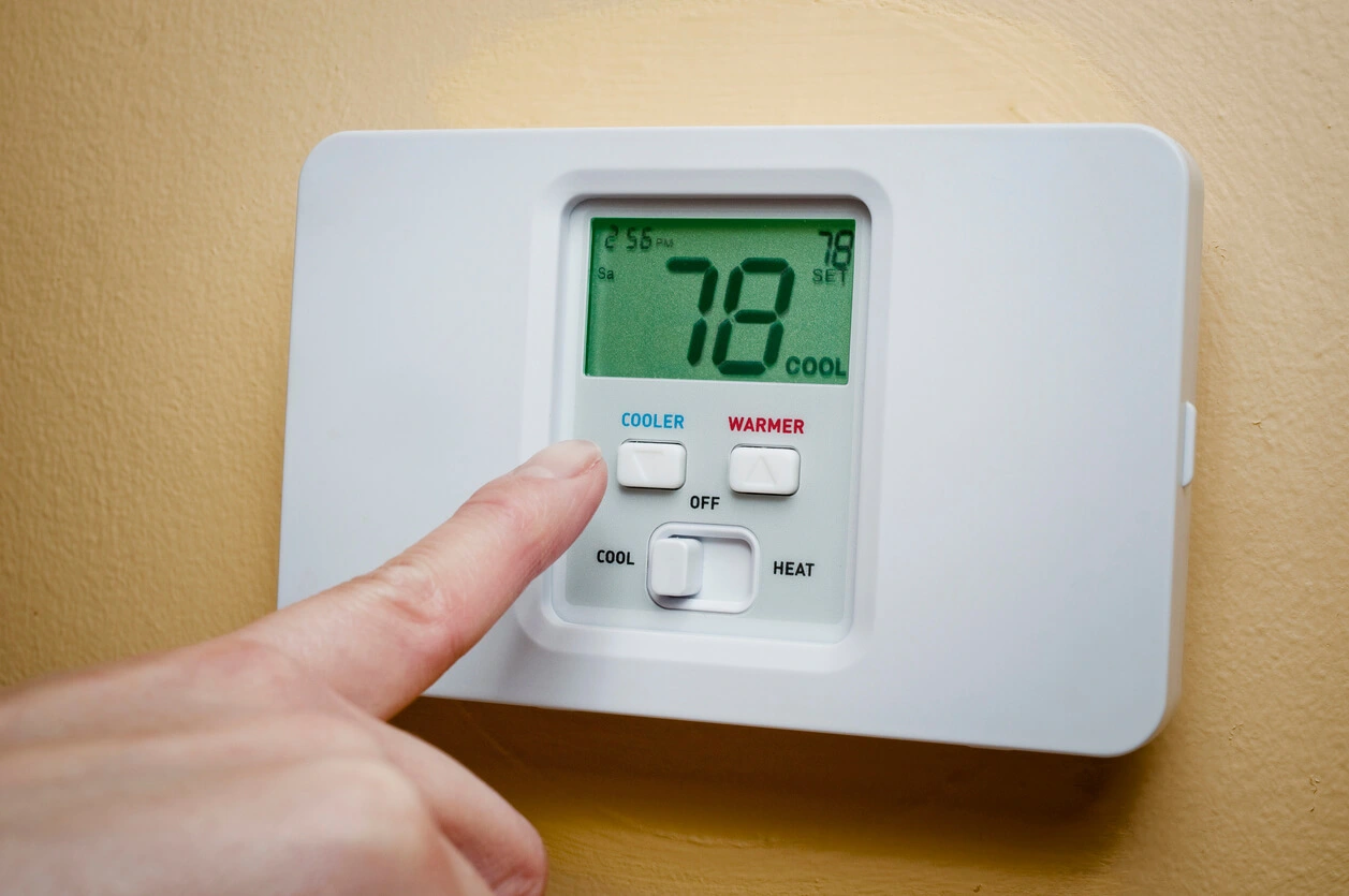 finger reaching to turning on the thermostat button or panel