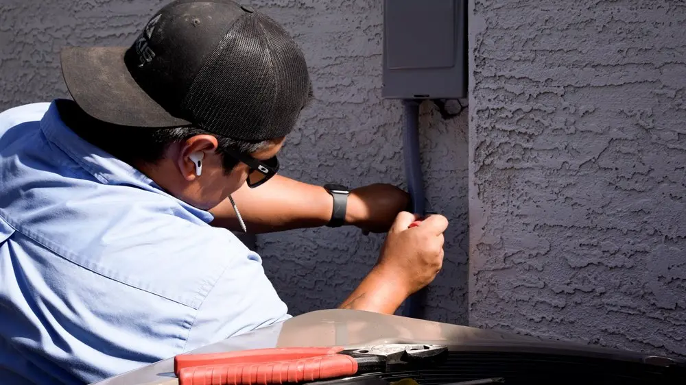 HVAC technician repairing an outdoor AC unit in Mesa, AZ