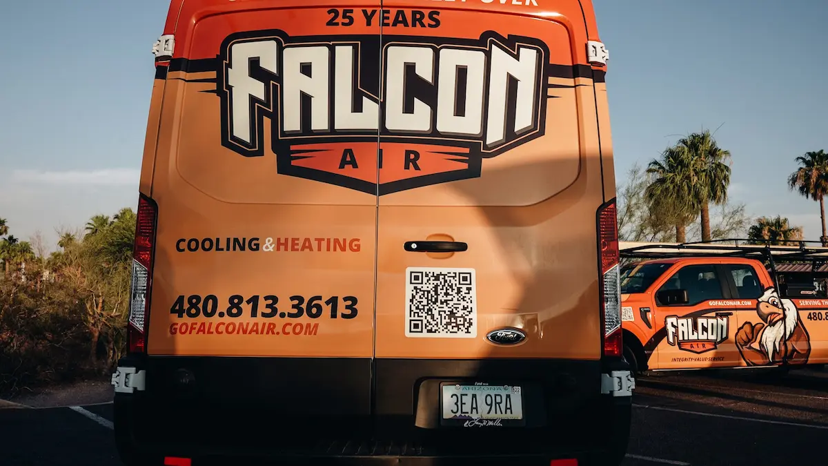 Falcon Air Conditioning service van parked with HVAC equipment and another company truck in the background