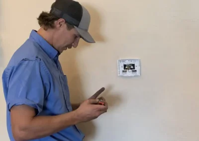 HVAC technician inspecting a thermostat in a Mesa, AZ home