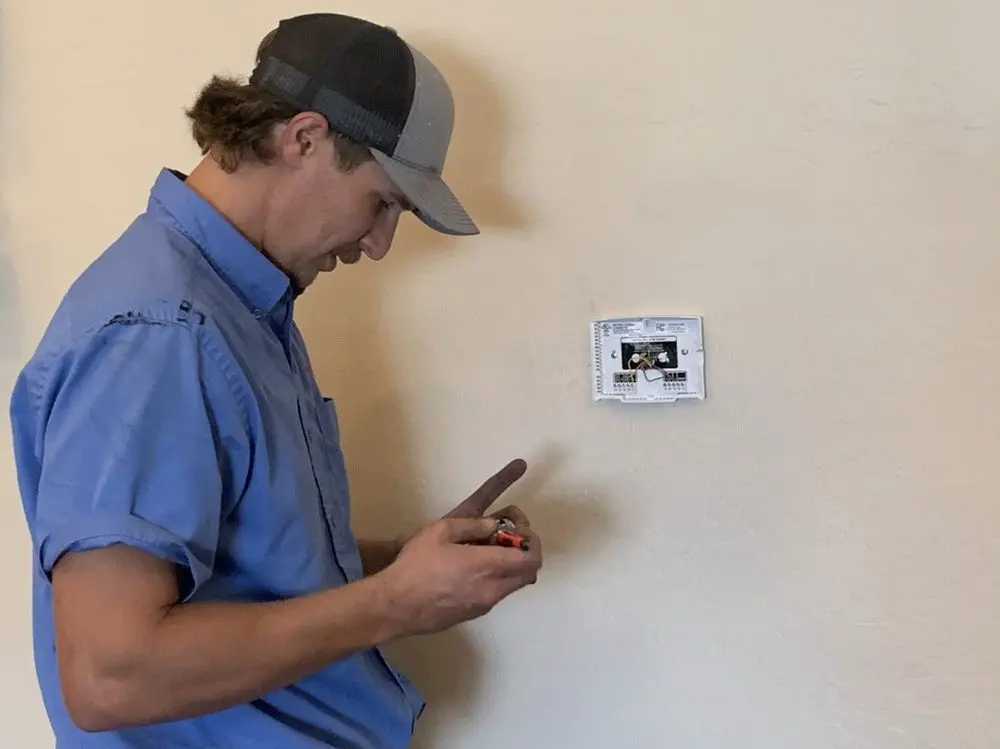 HVAC technician inspecting a thermostat in a Mesa, AZ home